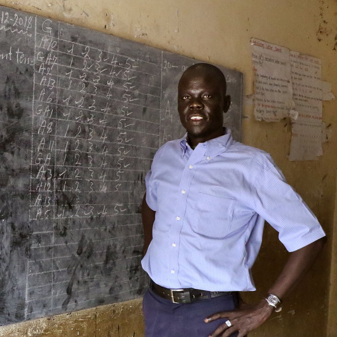 Teacher from South Sudan in front of a blackboard
